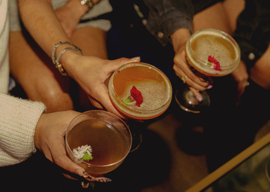 Three people holding Stir Sessions powdered craft cocktails or mocktails at a party.
