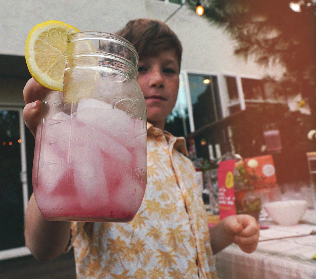 Kid holding a non alcoholic mocktail raspberry lemonade. Easy and fun to make. 