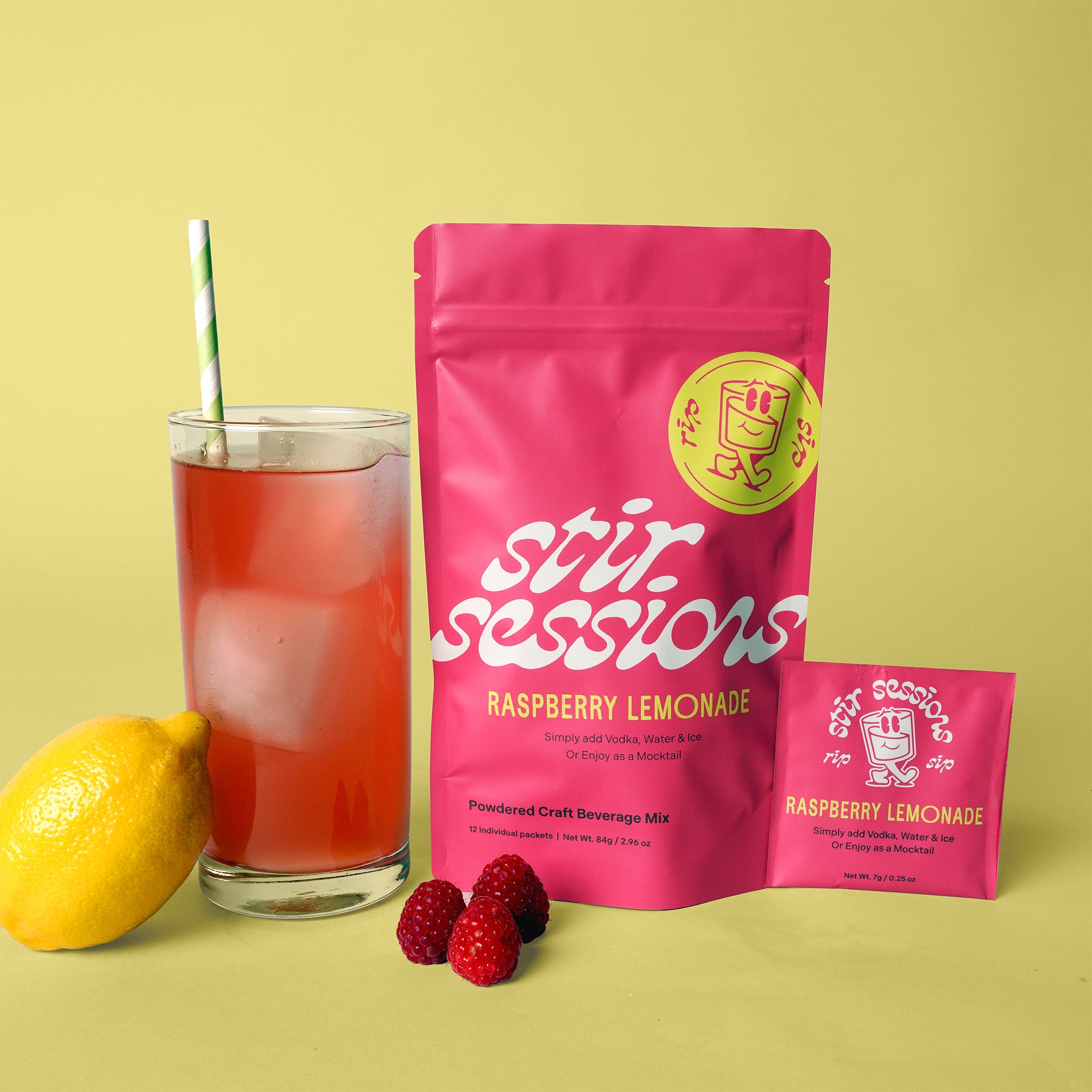 Pink 'Stir Sessions' Raspberry Lemonade powdered cocktail or mocktail drink beverage packaging with a glass of lemonade and lemon and raspberries on a yellow background.