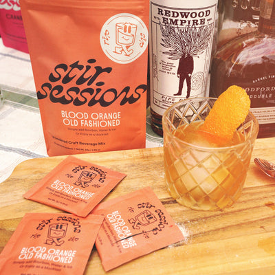 Stir Sessions Blood Orange Old Fashioned mix with a cocktail and orange peel on a wooden board.